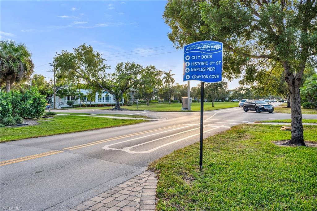 1100 9th Street South, Unit D201 Naples, FL 34102 - Photo 2 of 25 a sign board with flower plants and large trees