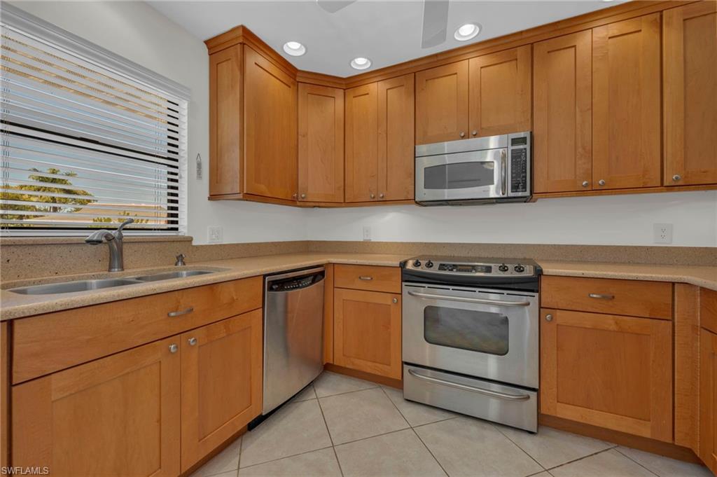 1100 9th Street South, Unit D201 Naples, FL 34102 - Photo 4 of 25 a kitchen with stainless steel appliances granite countertop a stove a sink and a microwave