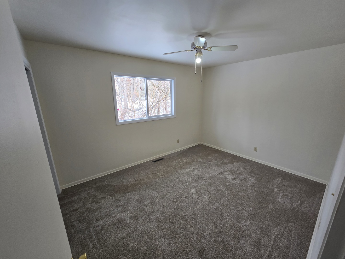 905 Hickory Road Woodstock, IL 60098 - Photo 26 of 32 an empty room with a chandelier fan and windows
