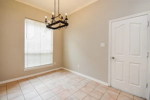 an empty room with chandelier fan and windows