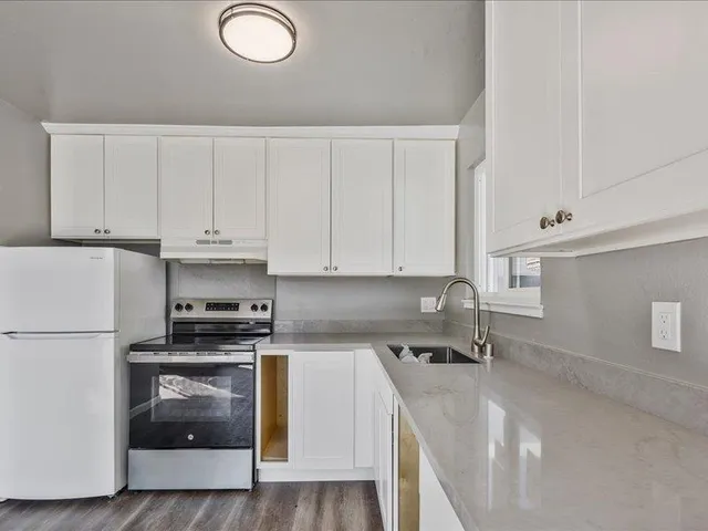 a kitchen with stainless steel appliances a stove a sink a refrigerator and white cabinets