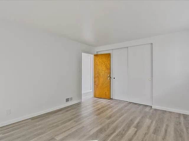 a view of empty room with wooden floor and fence