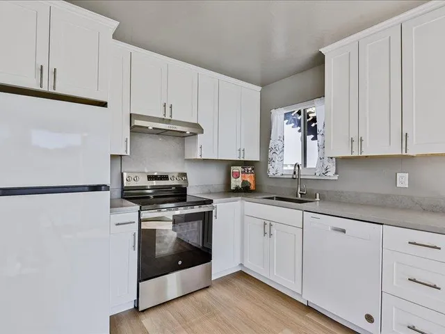 a kitchen with granite countertop white cabinets and white appliances