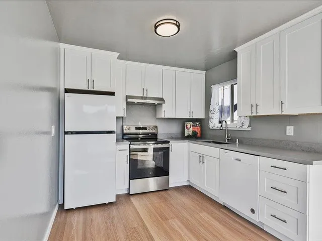 a kitchen with cabinets stainless steel appliances a sink and a window