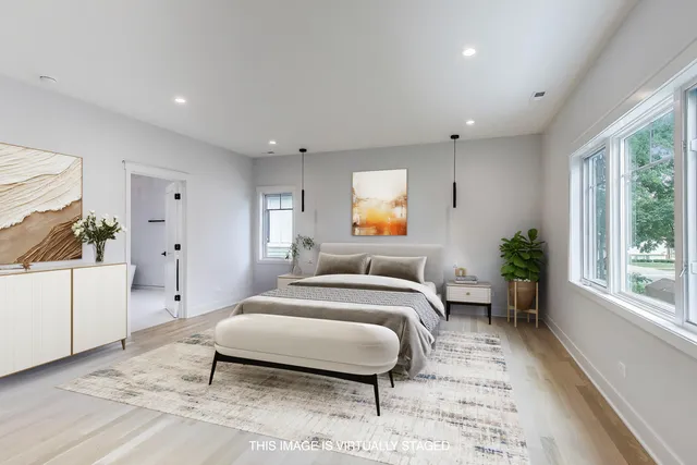 a spacious bedroom with a bed a mirror and a large window