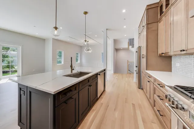a large kitchen with stainless steel appliances a sink stove and cabinets