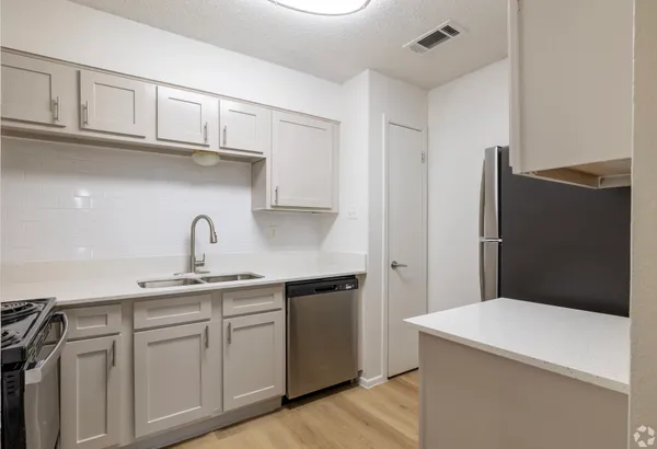 a kitchen with stainless steel appliances a sink dishwasher a refrigerator and cabinets