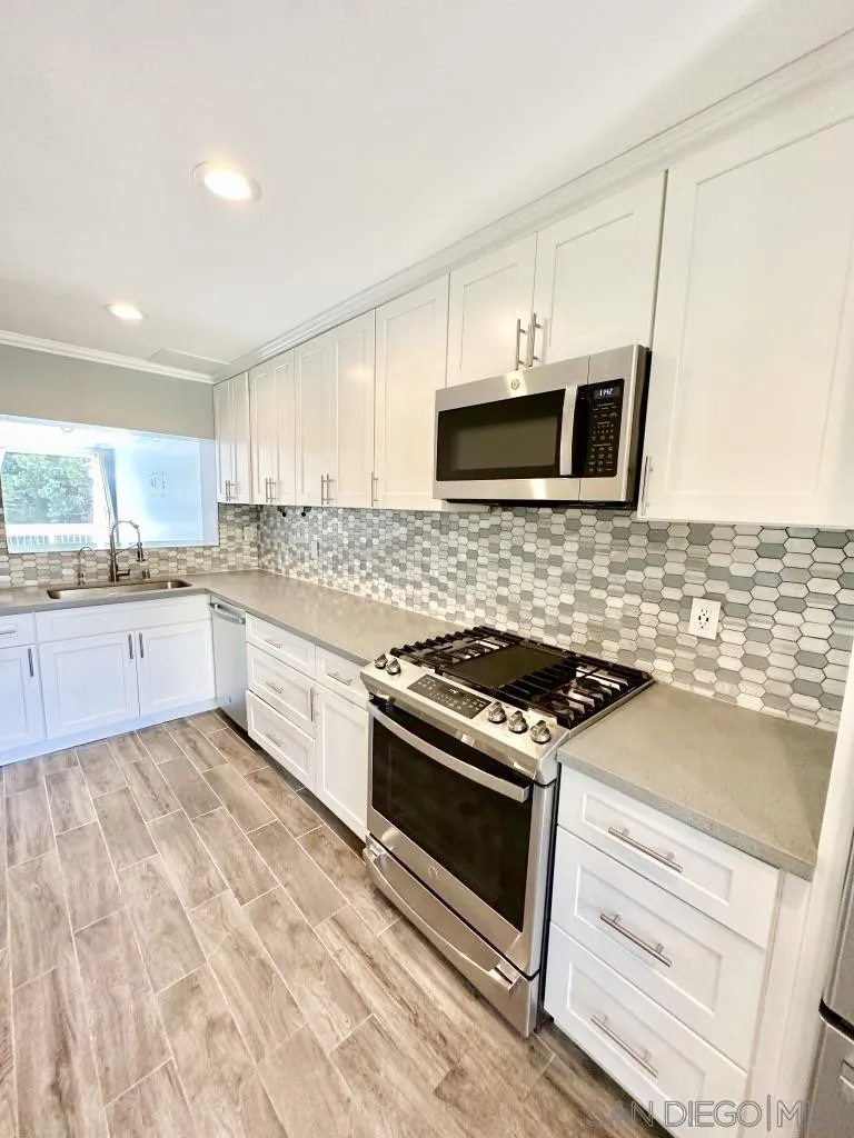 6855 Friars Road, Unit 14 San Diego, CA 92108 - Photo 12 of 31 a kitchen with stainless steel appliances white cabinets and stove top oven