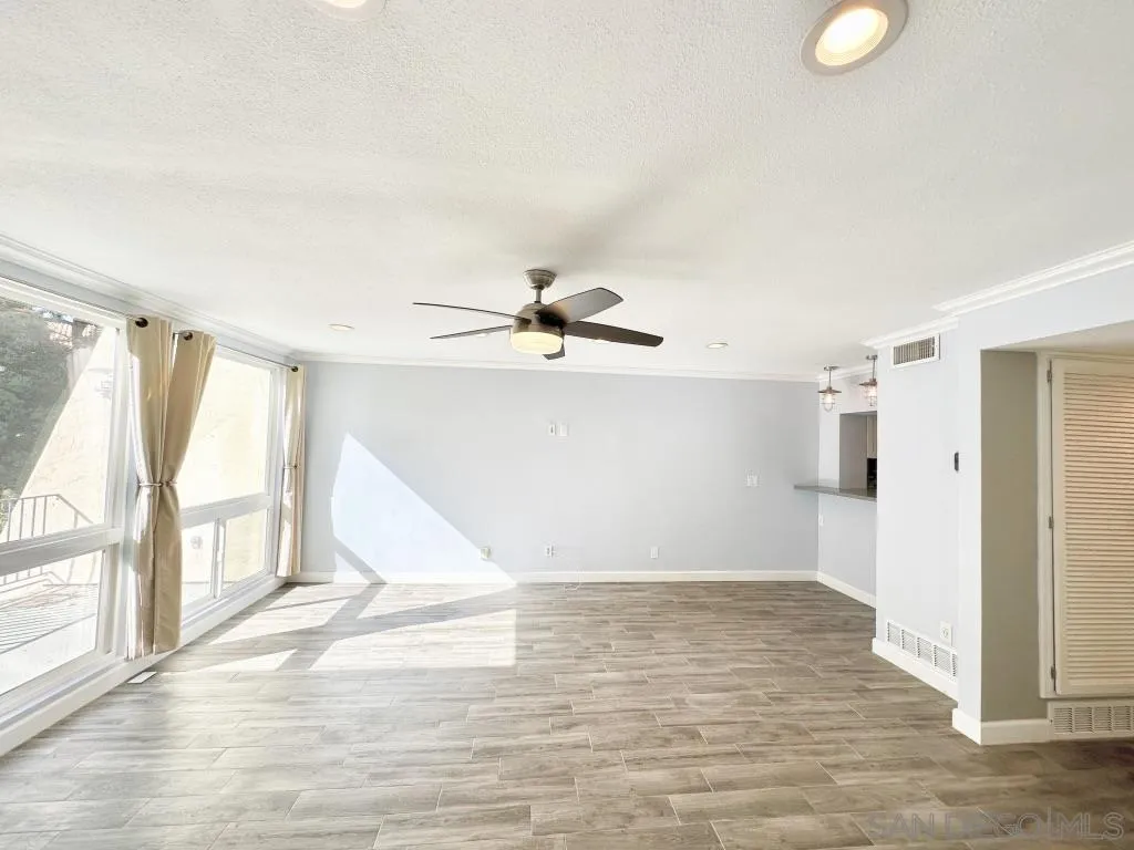 6855 Friars Road, Unit 14 San Diego, CA 92108 - Photo 5 of 31 a view of a livingroom with wooden floor and a ceiling fan