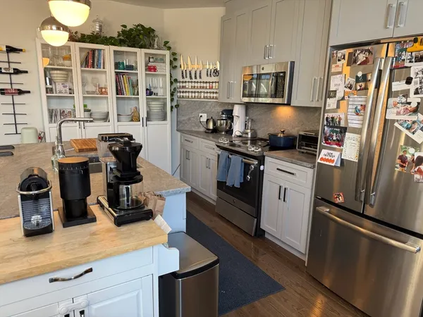 a kitchen with stainless steel appliances a stove a refrigerator a sink a counter space and cabinets