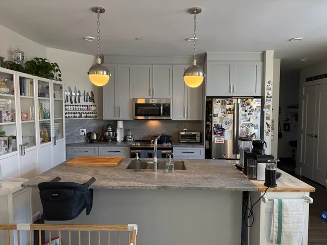 a kitchen with stainless steel appliances granite countertop a sink a stove and a wooden cabinets
