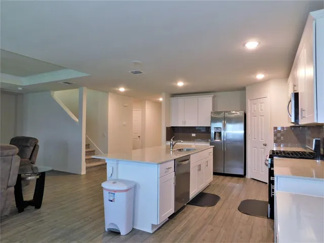 a kitchen with stainless steel appliances granite countertop a refrigerator a stove and a wooden floors