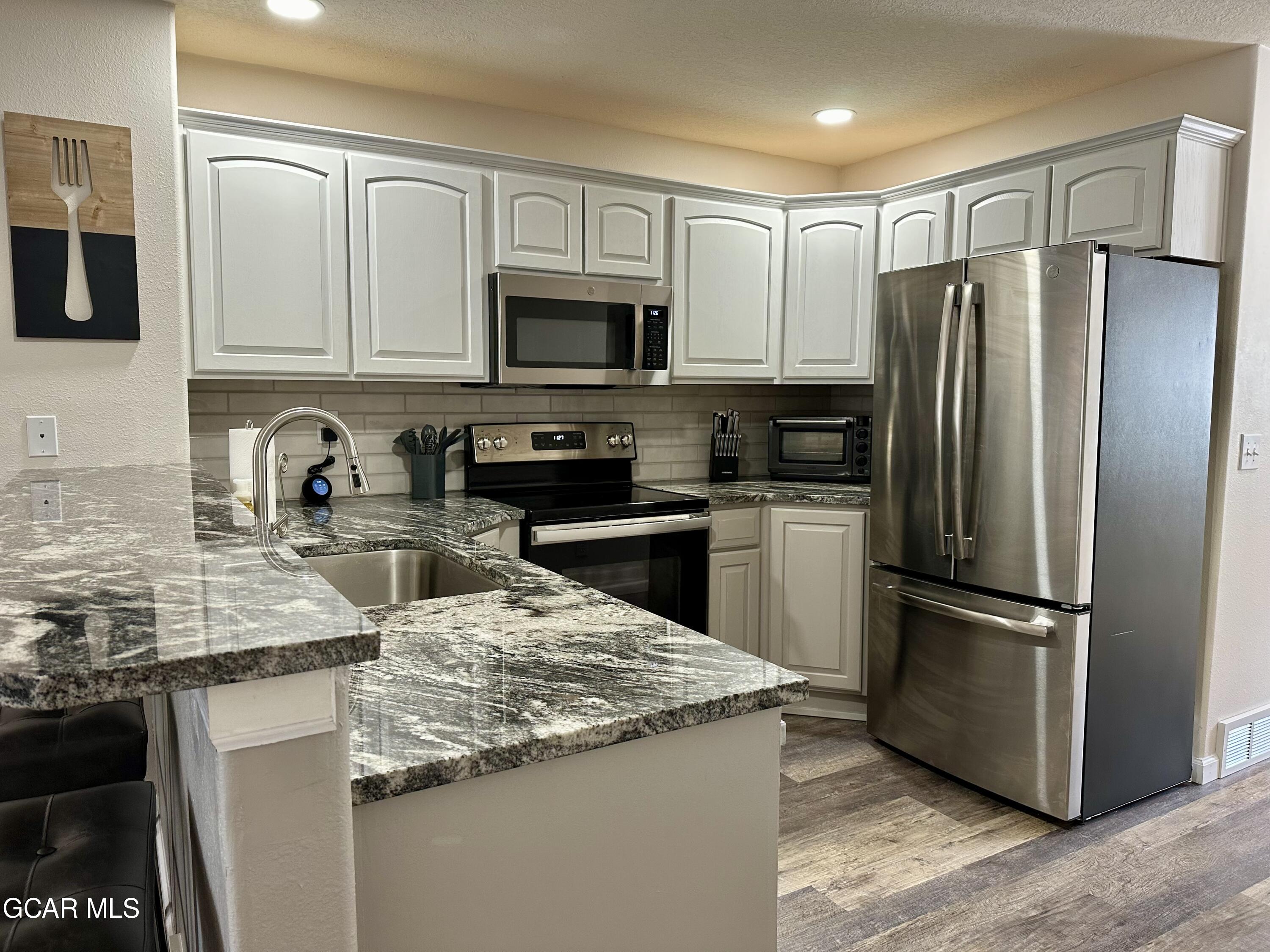 a kitchen with stainless steel appliances granite countertop a refrigerator stove microwave sink and cabinets