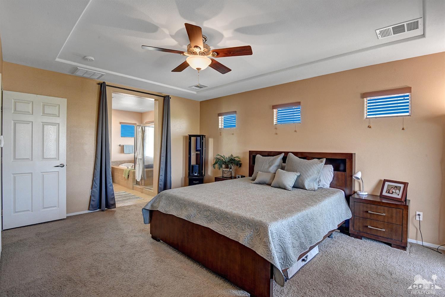 83447 Lone Star Road Indio, CA 92203 - Photo 30 of 47 a spacious bedroom with a large bed and a chandelier