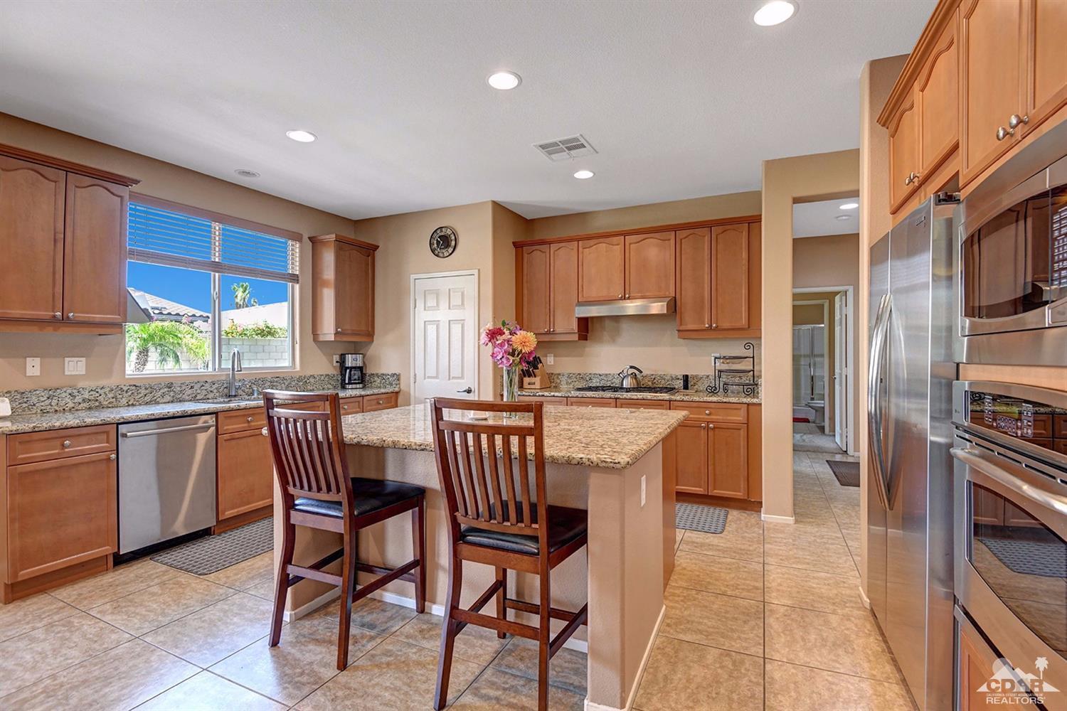 83447 Lone Star Road Indio, CA 92203 - Photo 8 of 47 a kitchen with stainless steel appliances granite countertop a stove a sink a refrigerator with a dining table and chairs