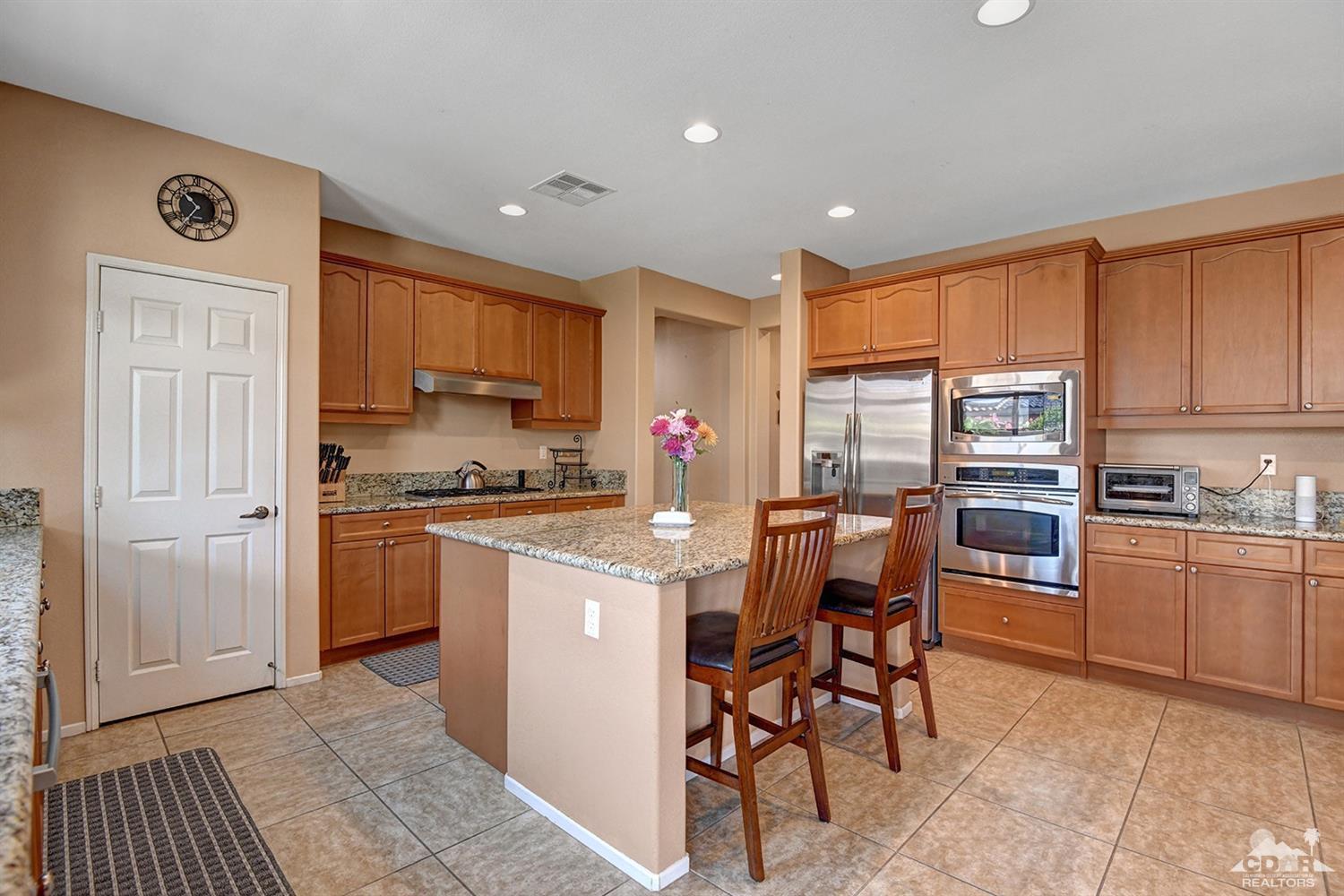 83447 Lone Star Road Indio, CA 92203 - Photo 10 of 47 a kitchen with kitchen island granite countertop wooden cabinets and stainless steel appliances