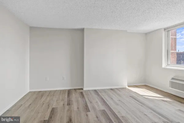 a view of an empty room with wooden floor & closet area
