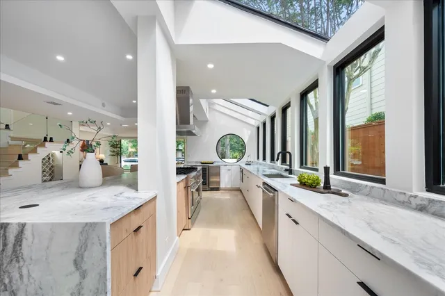 a large white kitchen with a large window and stainless steel appliances