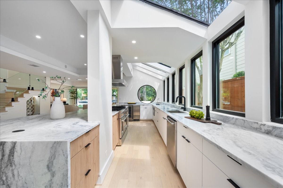 a large white kitchen with a large window and stainless steel appliances