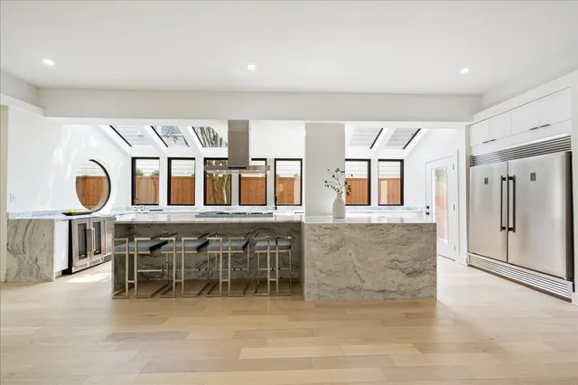 a view of a kitchen with kitchen island stainless steel appliances a sink and cabinets