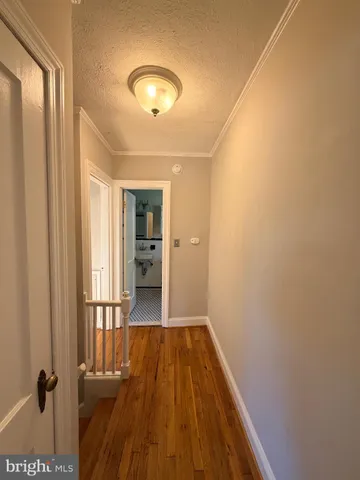 a view of a hallway with wooden floor and a bathroom