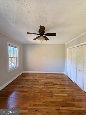 a view of empty room with wooden floor and window