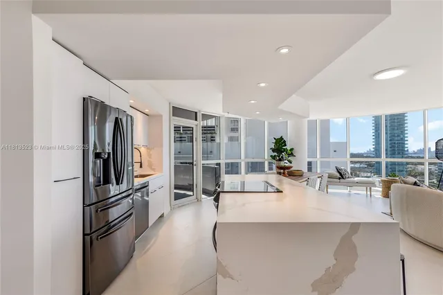 a living room with stainless steel appliances furniture and a kitchen view