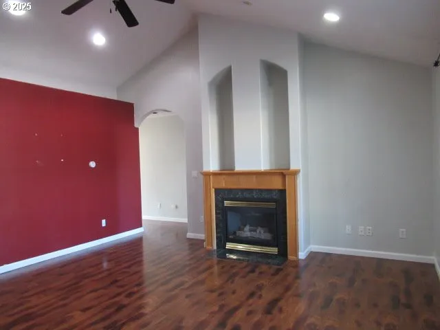 a view of an empty room with wooden floor and a fireplace
