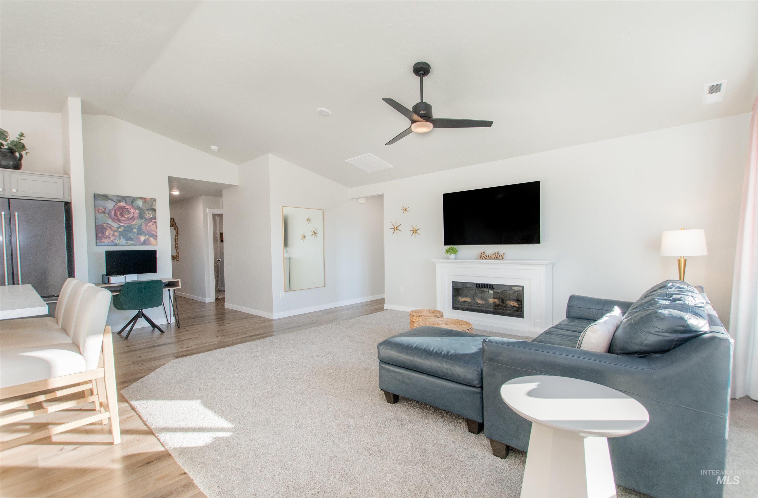 11289 West Langit Street Star, ID 83669 - Photo 12 of 33 Living area with a glass covered fireplace, lofted ceiling, light wood-style floors, and a ceiling fan