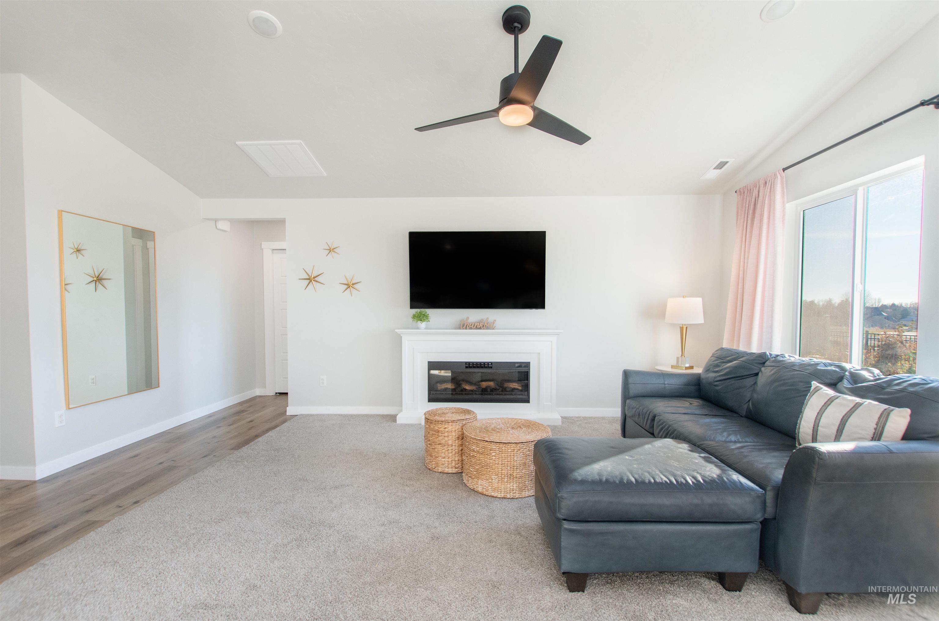 11289 West Langit Street Star, ID 83669 - Photo 8 of 33 Living area featuring a glass covered fireplace, a ceiling fan, lofted ceiling, and wood finished floors