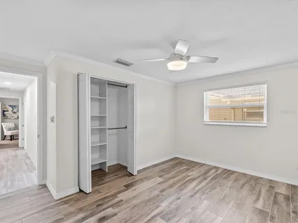 a view of empty room with wooden floor and ceiling fan