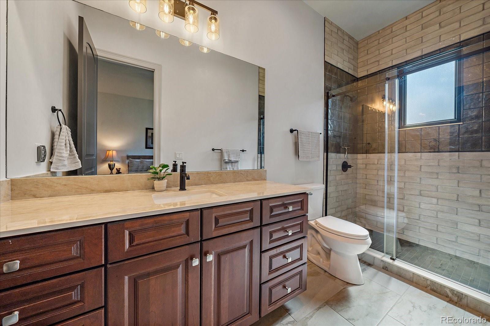 20132 East Shady Ridge Road Parker, CO 80134 - Photo 22 of 36 a bathroom with a sink toilet a mirror and shower