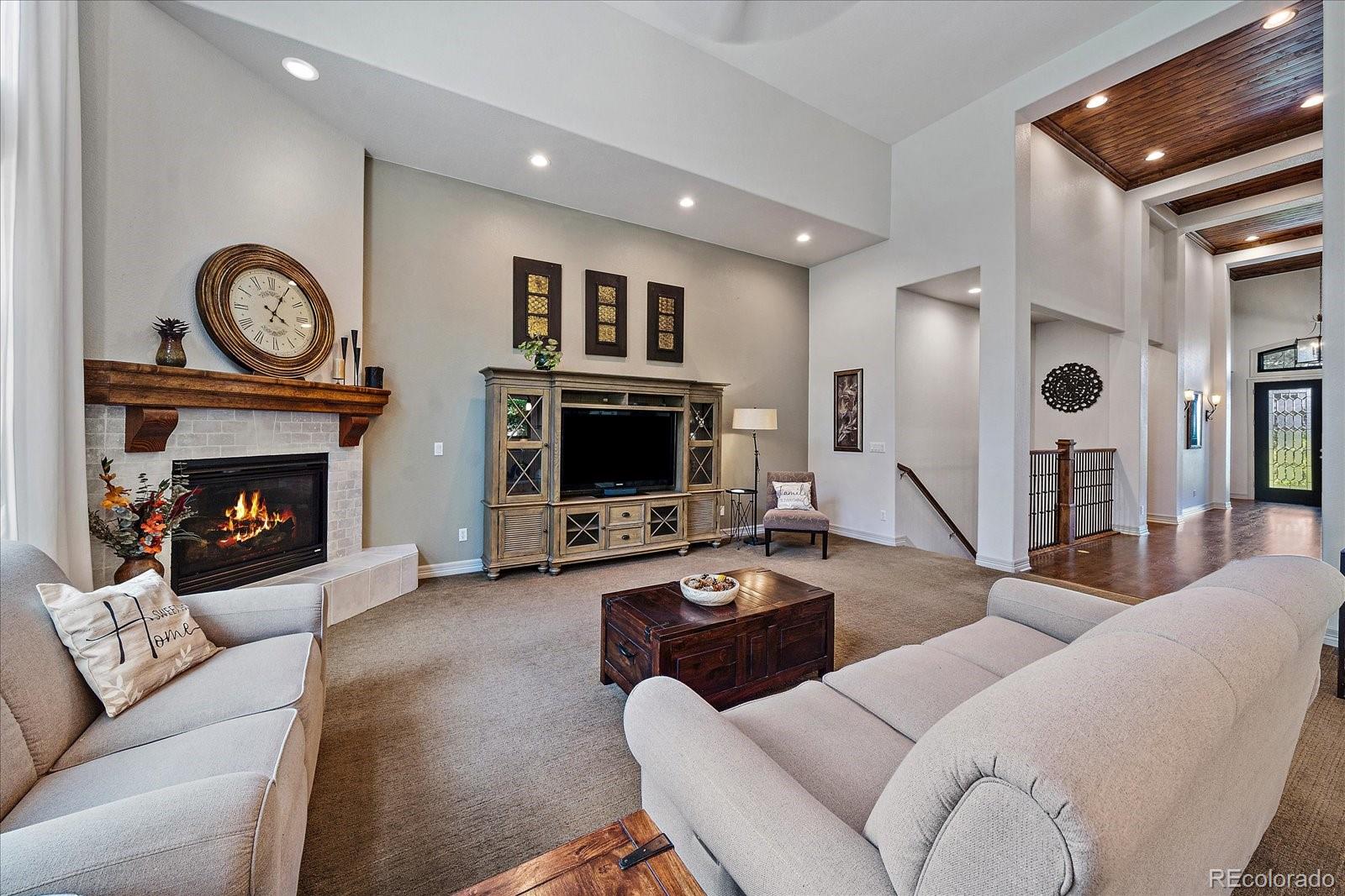 20132 East Shady Ridge Road Parker, CO 80134 - Photo 6 of 36 a living room with furniture a flat screen tv and a fireplace