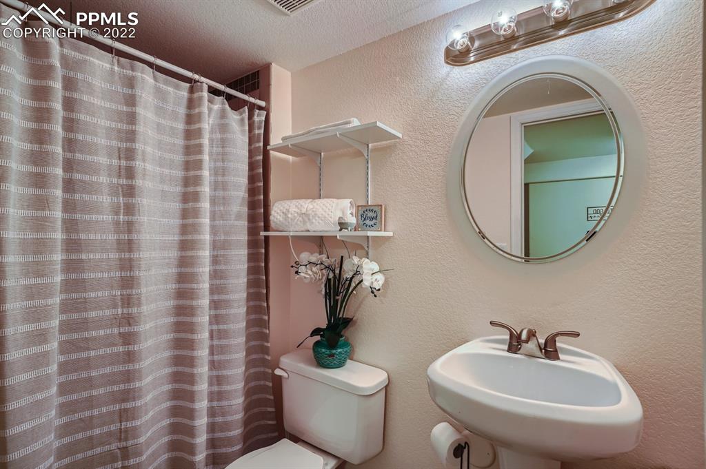 12118 Rio Secco Road Peyton, CO 80831 - Photo 21 of 23 a bathroom with a sink a mirror a toilet and a mirror