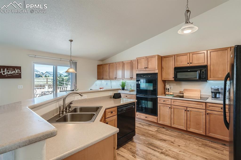 12118 Rio Secco Road Peyton, CO 80831 - Photo 7 of 23 a kitchen with stainless steel appliances a stove a sink a microwave and wooden cabinets