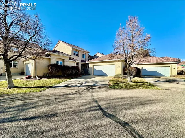 a view of a white house with a large tree
