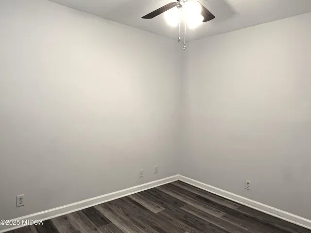an empty room with wooden floor and fan