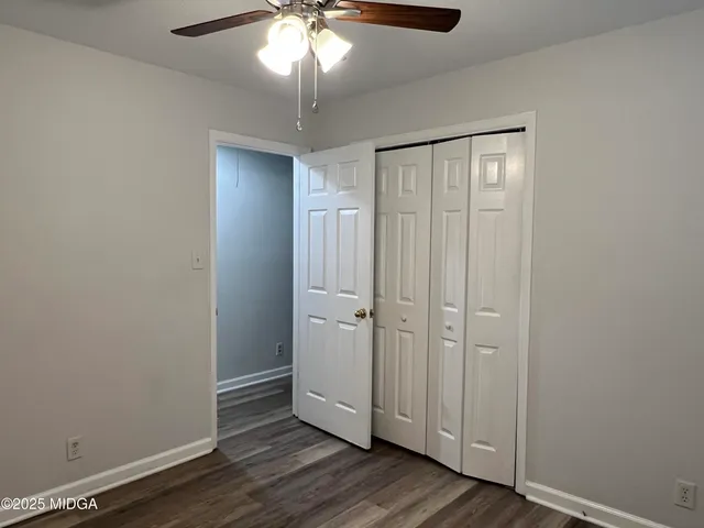 an empty room with wooden floor closet and windows