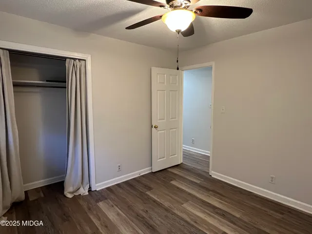 an empty room with wooden floor a ceiling fan