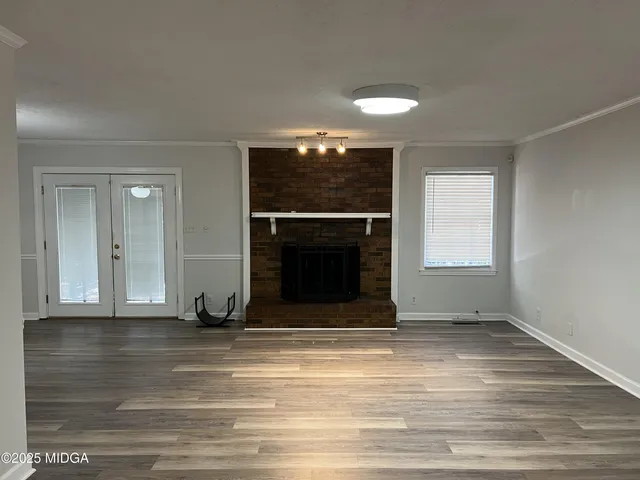 an empty room with wooden floor fireplace and window