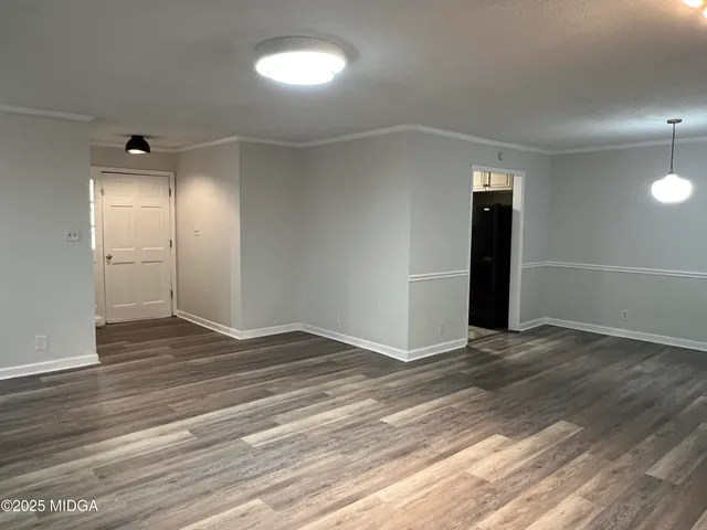 an empty room with wooden floor & windows