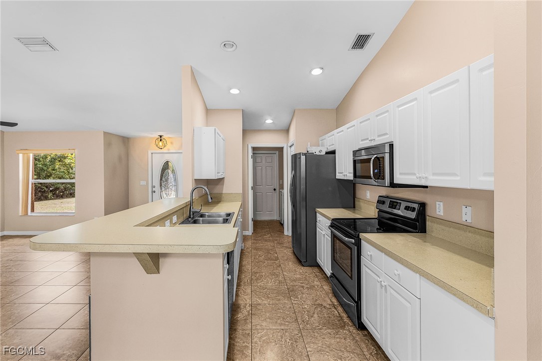 1644 Dawnview Street North Port, FL 34288 - Photo 10 of 32 a kitchen with stainless steel appliances kitchen island a white stove top oven a sink a refrigerator and white cabinets