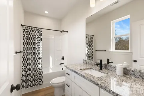 a bathroom with a granite countertop sink toilet and shower