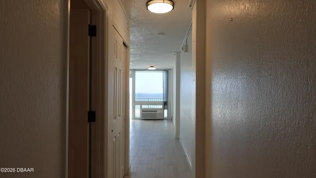 a view of a hallway with wooden floor and a bathroom