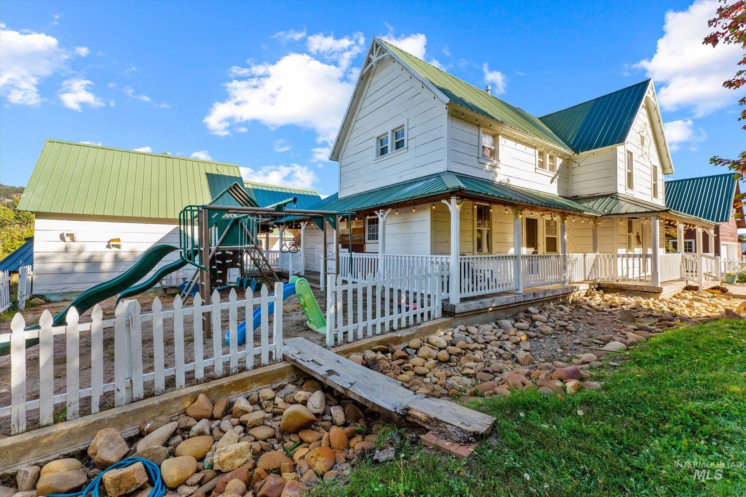 315 South Middlefork Road Garden Valley, ID 83622 - Photo 2 of 49 View of home's exterior featuring a metal roof, covered porch, and a playground