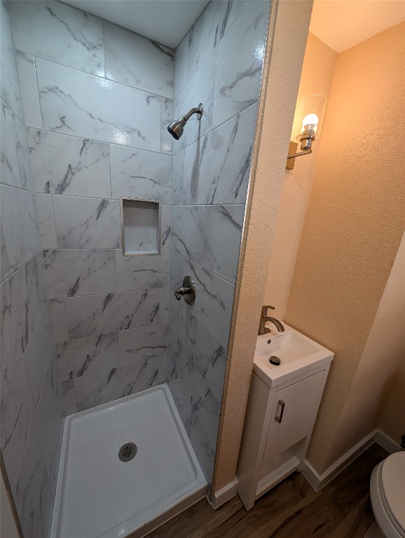 320 Laredo Street Lockhart, TX 78644 - Photo 13 of 27 Bathroom with a stall shower, wood finished floors, vanity, and a textured wall