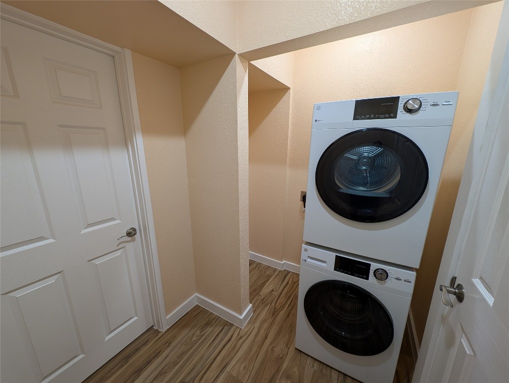 320 Laredo Street Lockhart, TX 78644 - Photo 19 of 27 Washroom with wood finished floors, stacked washer / drying machine, and a textured wall