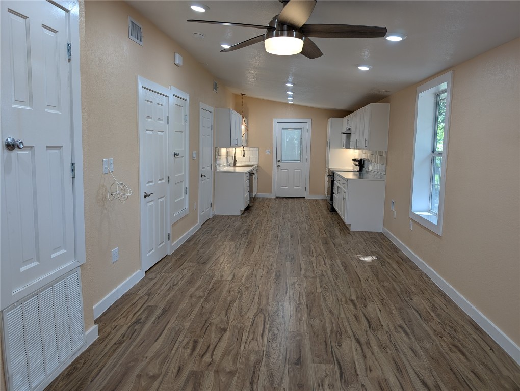 320 Laredo Street Lockhart, TX 78644 - Photo 3 of 27 Kitchen with white cabinetry, backsplash, light countertops, dark wood-style floors, and lofted ceiling