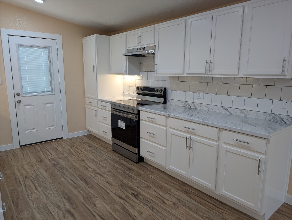 320 Laredo Street Lockhart, TX 78644 - Photo 4 of 27 Kitchen featuring electric range, white cabinetry, dark wood-type flooring, backsplash, and under cabinet range hood