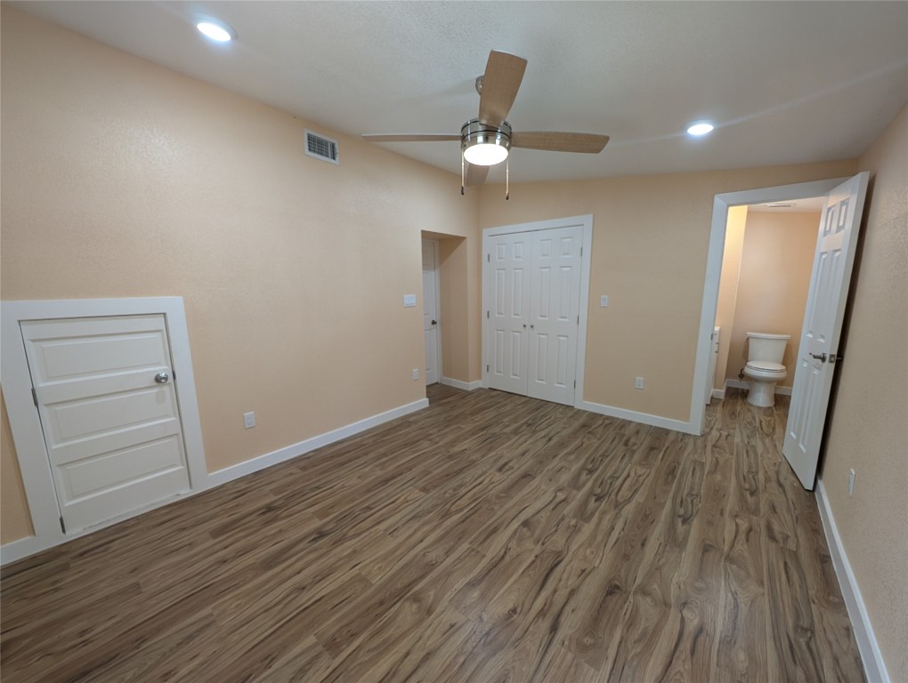 320 Laredo Street Lockhart, TX 78644 - Photo 10 of 27 Unfurnished bedroom featuring recessed lighting, wood finished floors, a closet, a ceiling fan, and ensuite bathroom